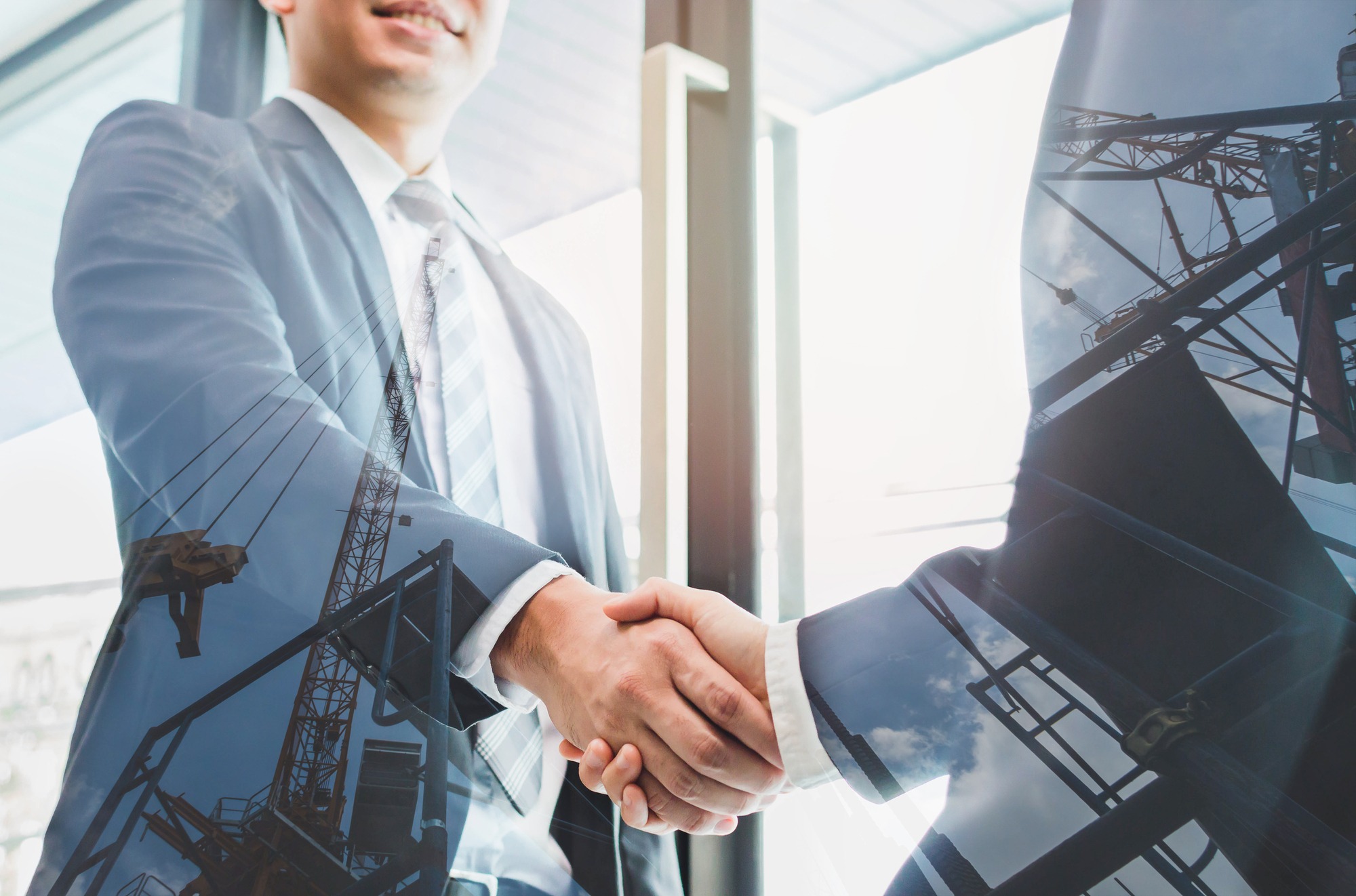 Double exposure of two businessmen reaching an agreement and making handshake